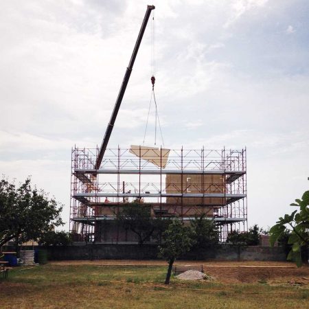 Foto der Baustelle für den Um- und Aufbau eines Familienhauses in Muggia Trieste Italien Montage mit Autokran der Tragwände des Dachgeschosses und des Daches aus Holz